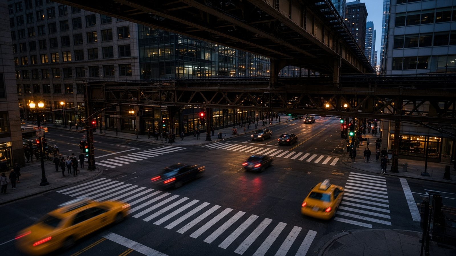 Elevated view of a Chicago Loop intersection at blue hour with traffic signals, crosswalks, and the elevated train tracks overhead
